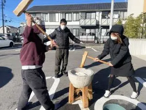 冬場、外で元気に餅つきをするスタッフと見守る利用者